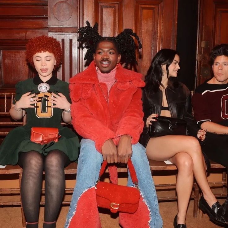 three people sitting on a bench with one holding a purse and the other wearing boots