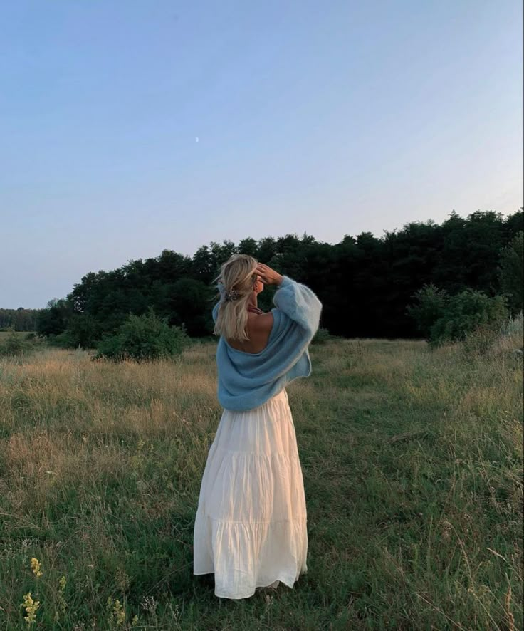 a woman in a white dress standing in a field