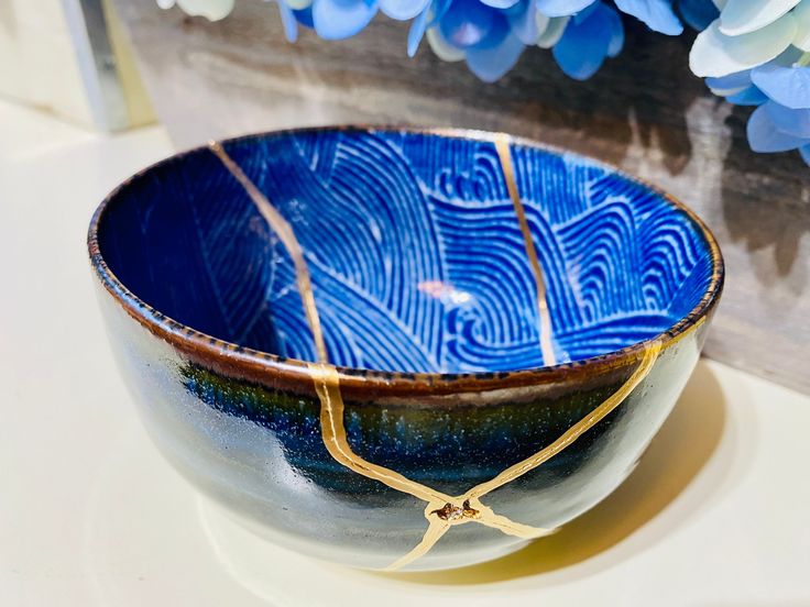 a blue and white bowl sitting on top of a table next to some purple flowers