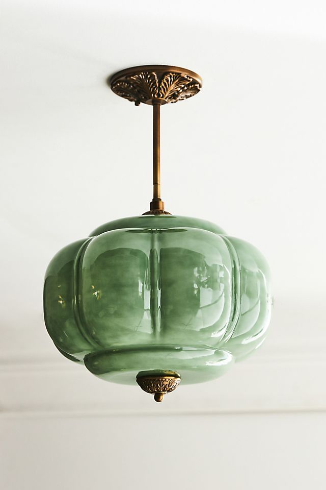 a green glass light fixture hanging from a ceiling in a room with white walls and ceilings