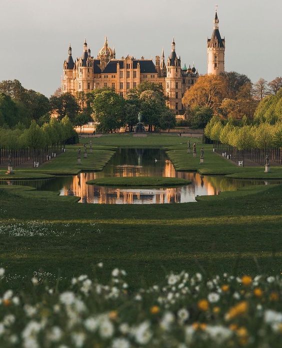 a large castle with a pond in front of it