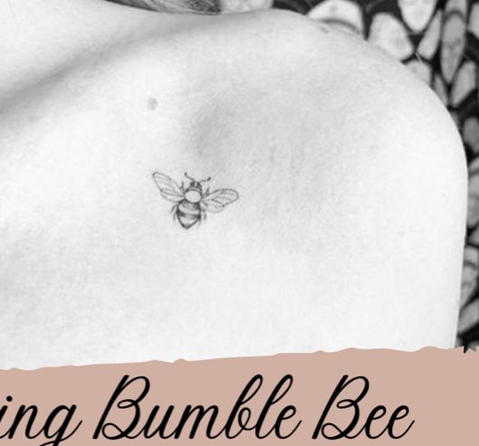 a black and white photo of a woman's chest with a bee tattoo on it