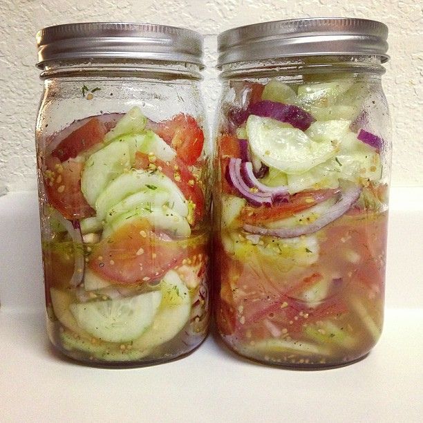 two mason jars filled with pickles and tomatoes