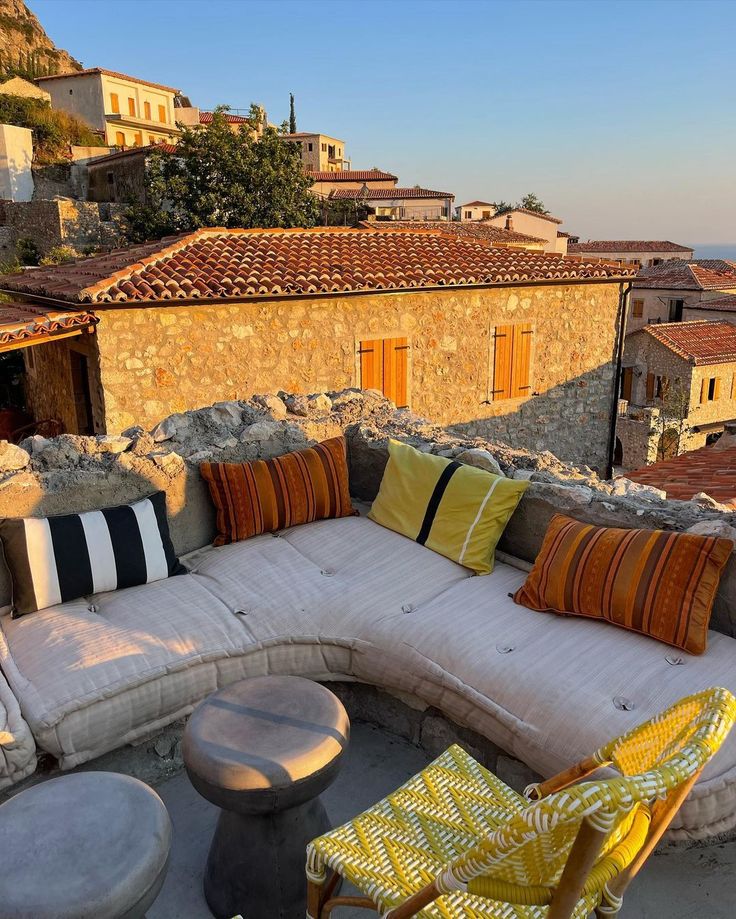 an outdoor seating area with yellow and orange pillows on the couches, overlooking buildings in the background