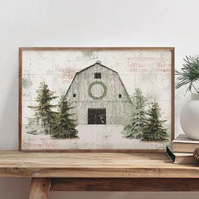 a white vase sitting on top of a wooden table next to a framed photo with a barn in the background