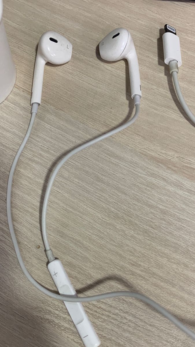 two ear buds connected to each other on top of a wooden table next to a cup