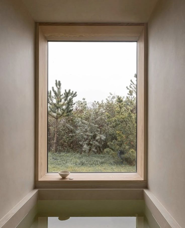 an empty room with a large window looking out at the trees outside in front of it