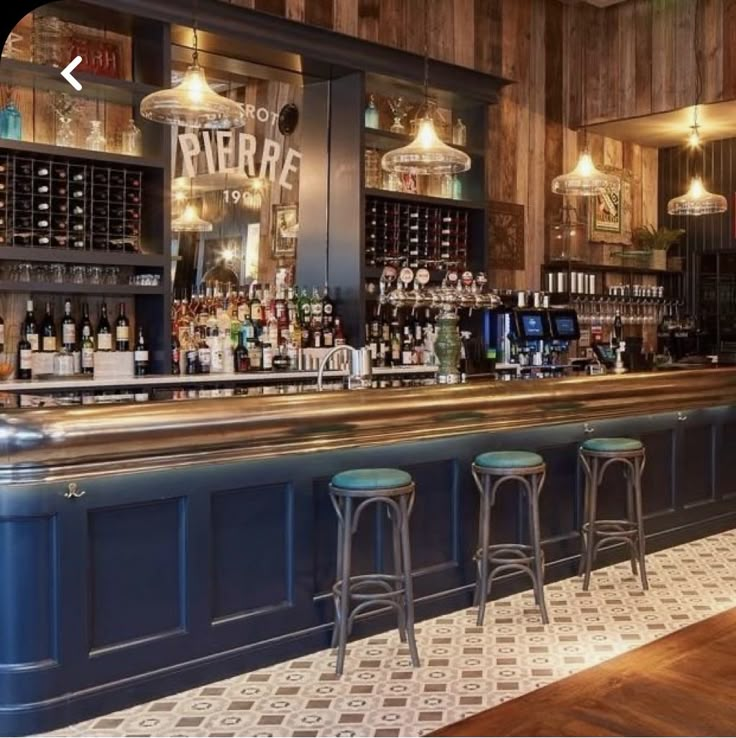 a bar with stools and bottles behind it