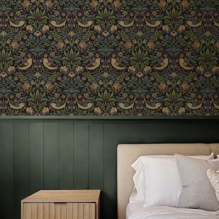 a bed sitting next to a green wall with a wooden night stand on top of it