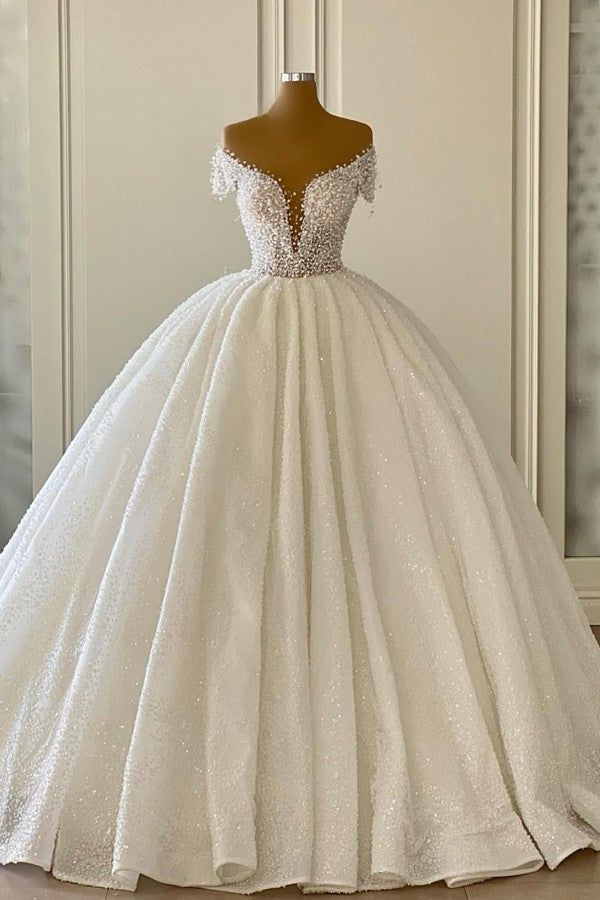 a white ball gown on display in front of a wall with a mannequin