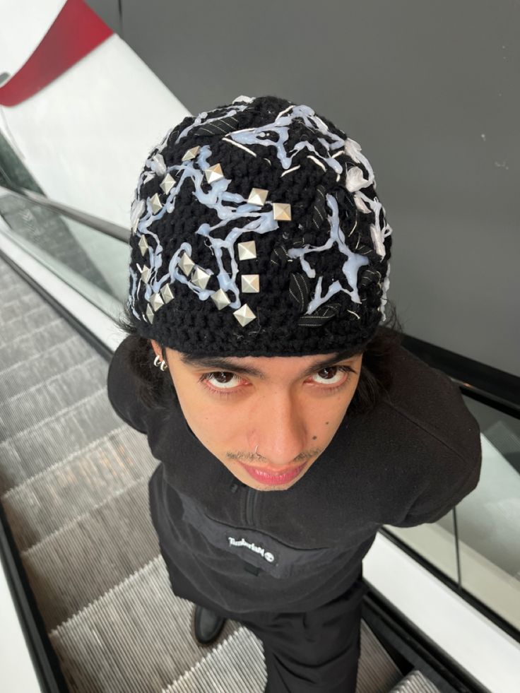 a young man wearing a black and white hat on an escalator in a building