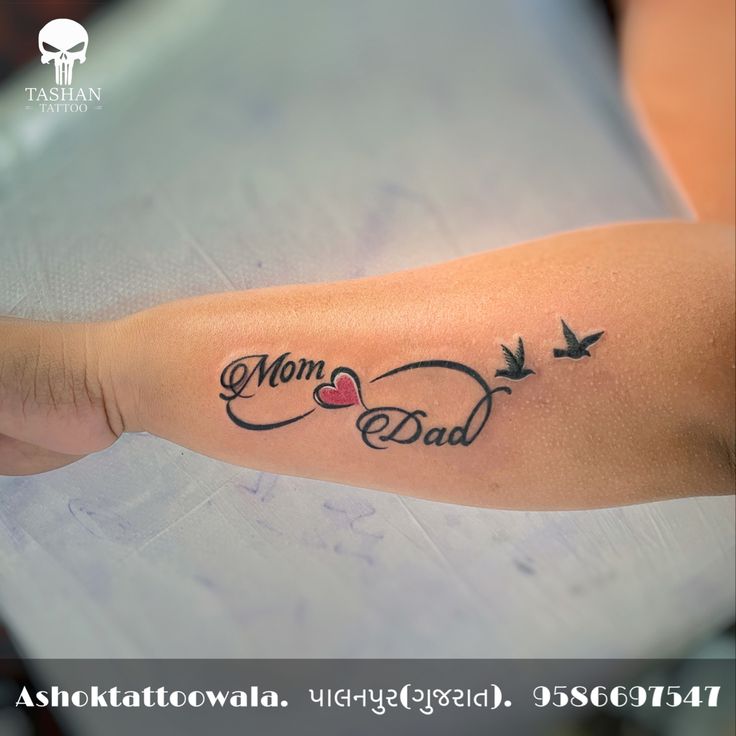 a woman's arm with the words mom, dad and two birds on it