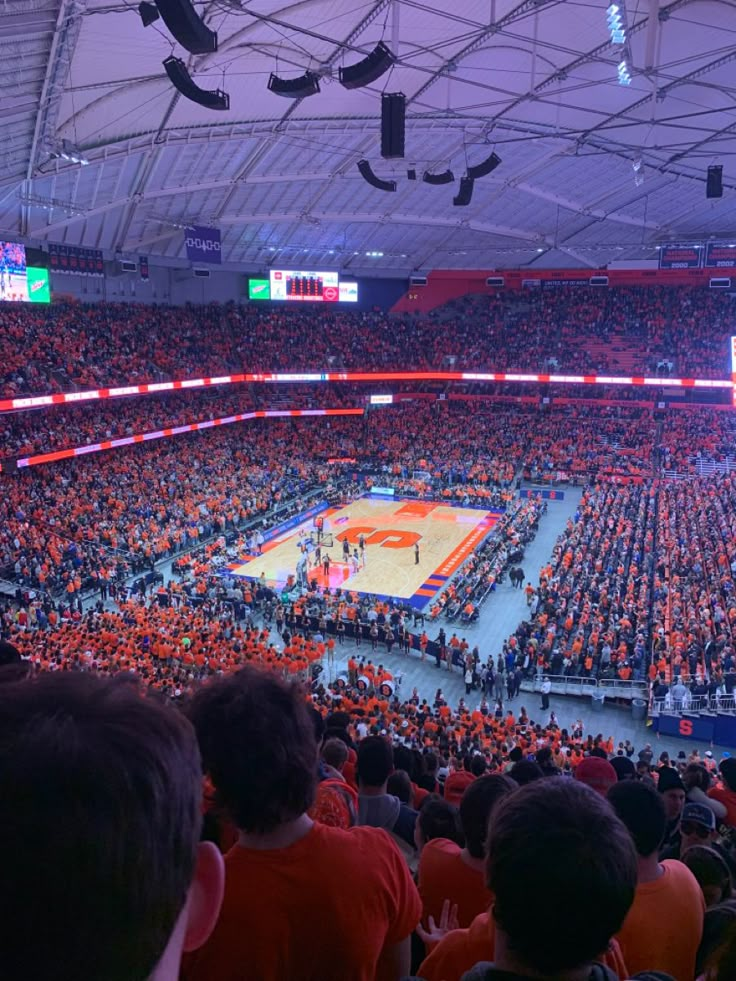 an orange and blue basketball game is being played in a large arena with people sitting on the sidelines