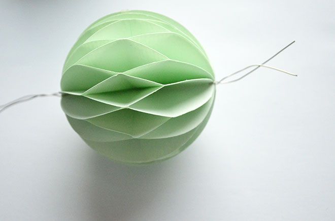 an origami ball on a white surface with string attached to it and two other objects in the background