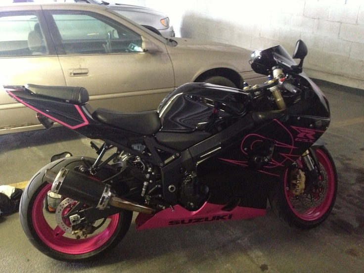 a black and pink motorcycle parked next to a car