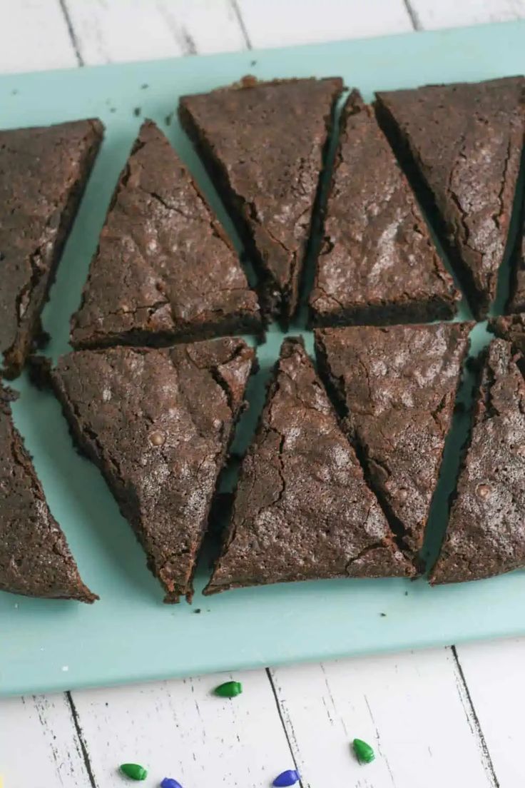 chocolate brownies cut into squares on a blue plate with green and white confetti