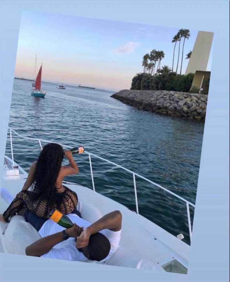 a man and woman sitting on the back of a boat in the ocean drinking from bottles