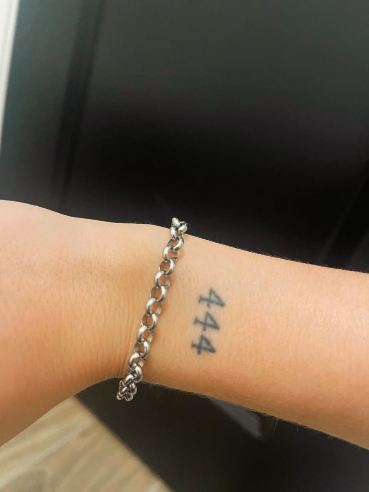 a person with a tattoo on their arm has a chain around his wrist and the number four