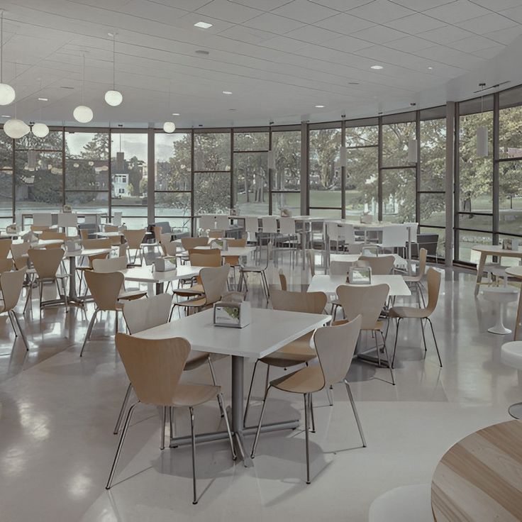 an empty restaurant with tables and chairs in front of large glass windows that overlook the park