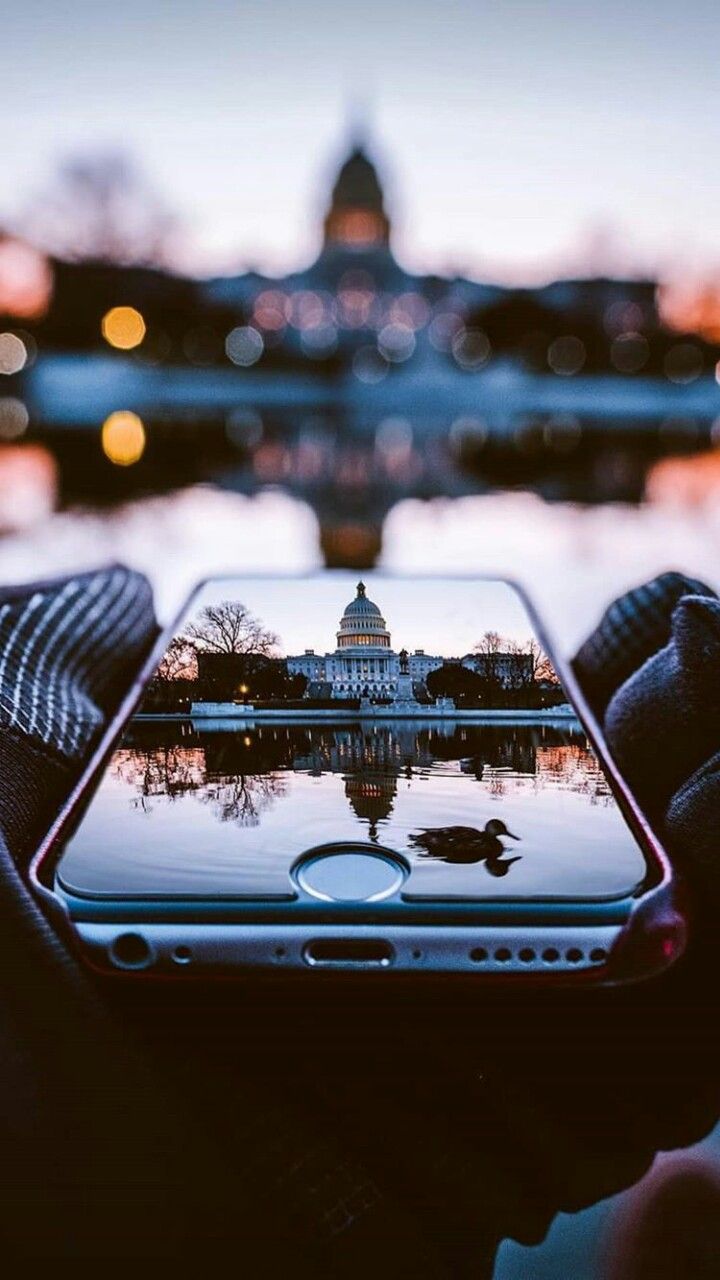 someone holding up their cell phone with the capitol building in the background