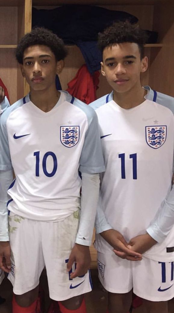 three young men standing next to each other in soccer uniforms