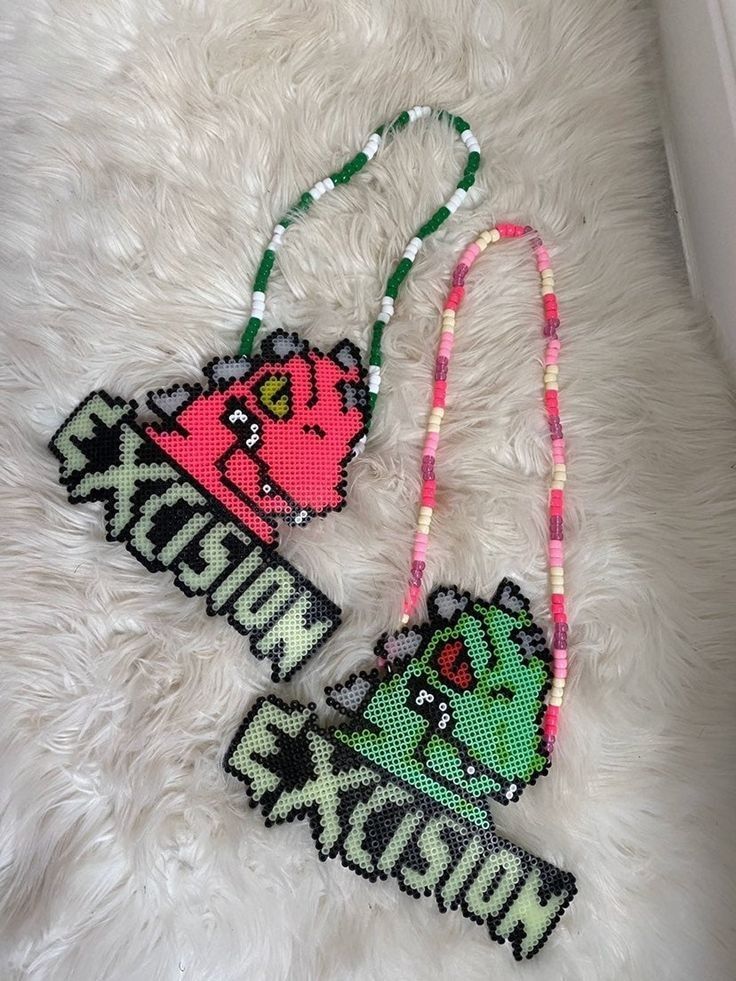 two necklaces that have been made to look like cartoon characters on them, one is pink and the other is green