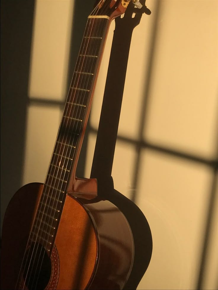 an acoustic guitar sitting in front of a window