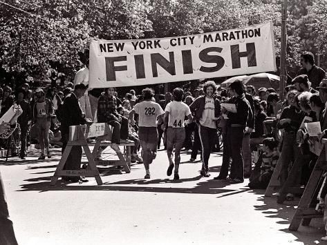 a group of people walking down a street holding up a sign that says new york city marathon finish