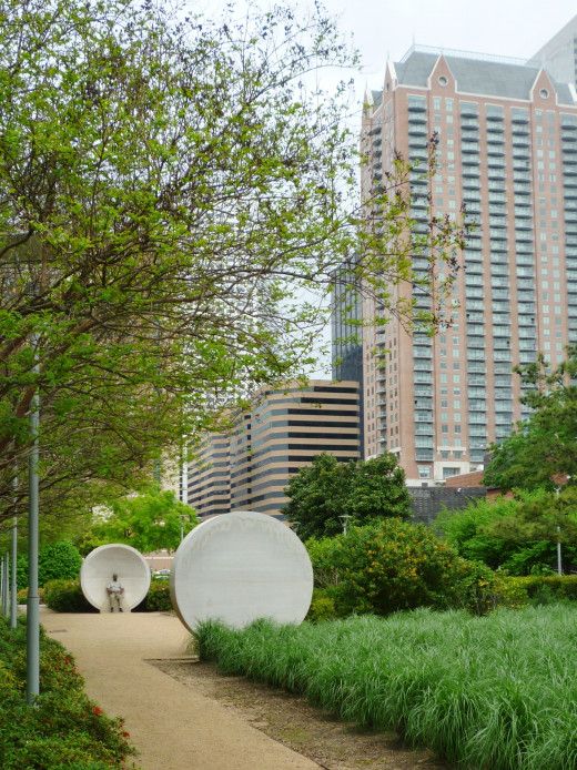 two large white plates sitting on top of a lush green field next to tall buildings