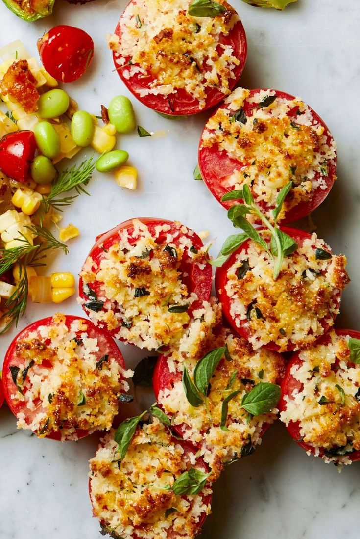 tomatoes and other vegetables are arranged on a white surface with some sprinkled parmesan cheese