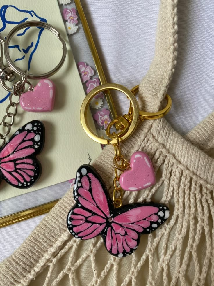 a pink butterfly keychain sitting on top of a white bag next to a card