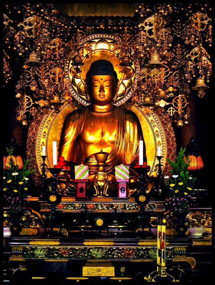 a golden buddha statue surrounded by candles and decorations