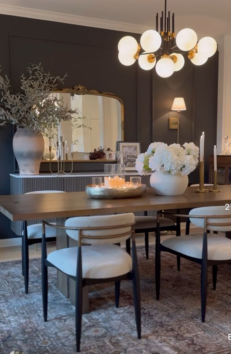 a dining room table with chairs and vases on it in front of a mirror