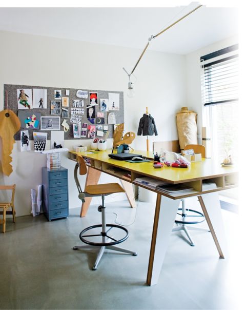 a room with a desk, chair and pictures on the wall above it is also a window