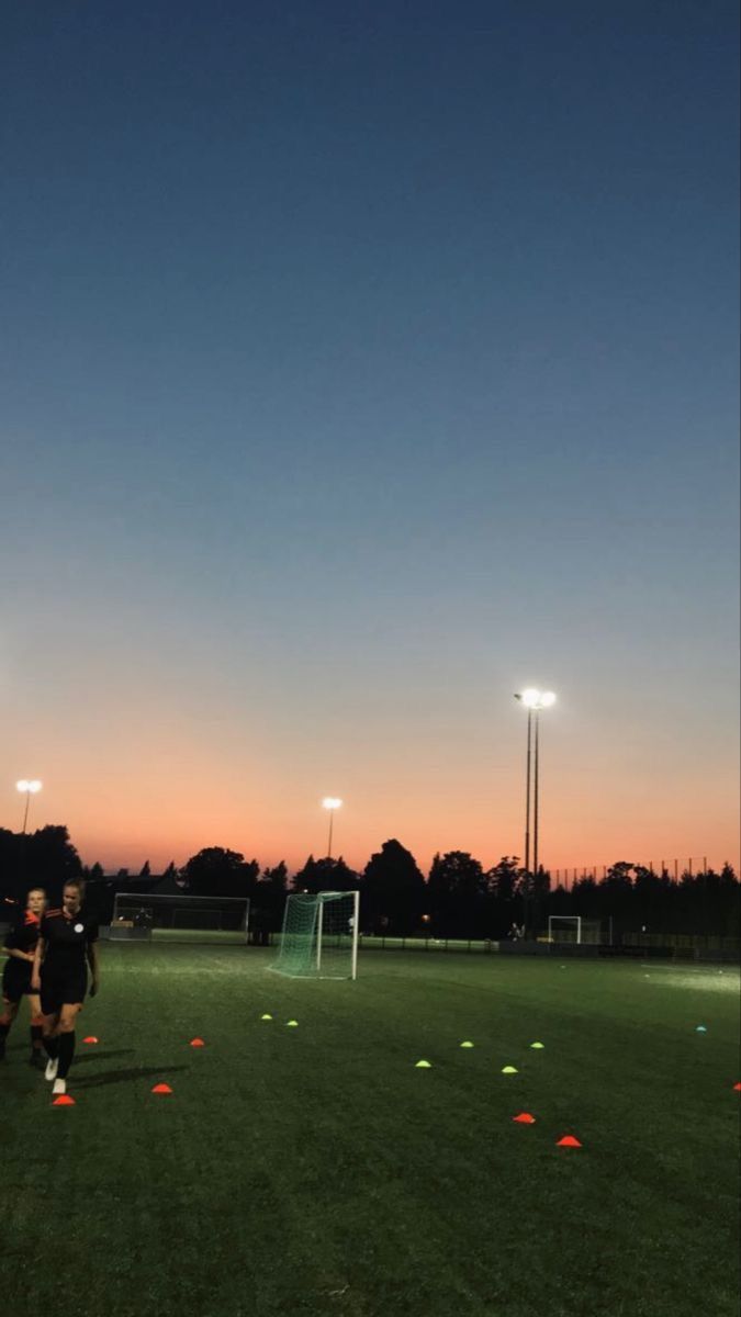 two soccer players are on the field at sunset