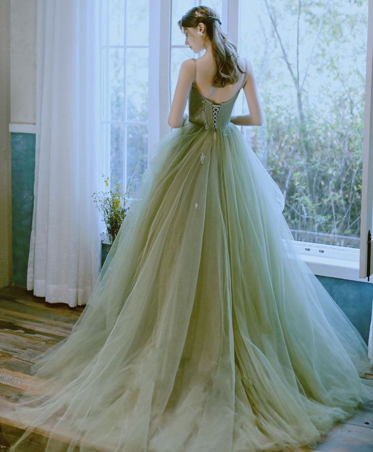 a woman in a green dress looking out the window