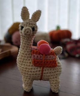 a small crocheted llama with a ball in its mouth on a table