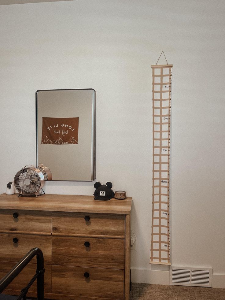 a wooden dresser sitting next to a tall clock on top of a wooden dresser under a mirror