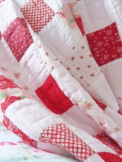 a red and white quilt on top of a bed