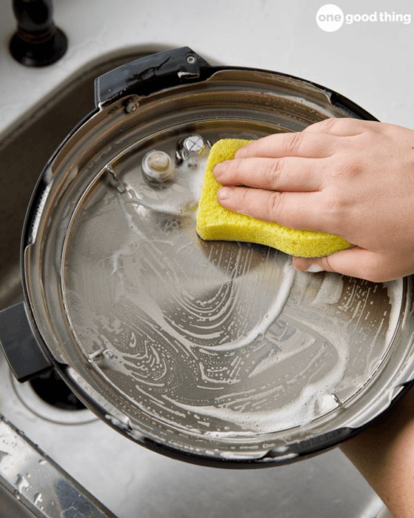 a person is cleaning a sink with a yellow sponge on the top of it and holding a rag in their hand