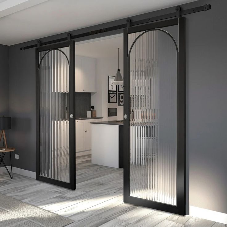 an open glass door leading to a kitchen and living room with grey walls, wood flooring and white furniture