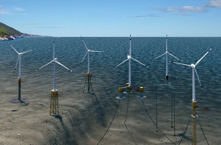 several wind turbines in the water on a beach