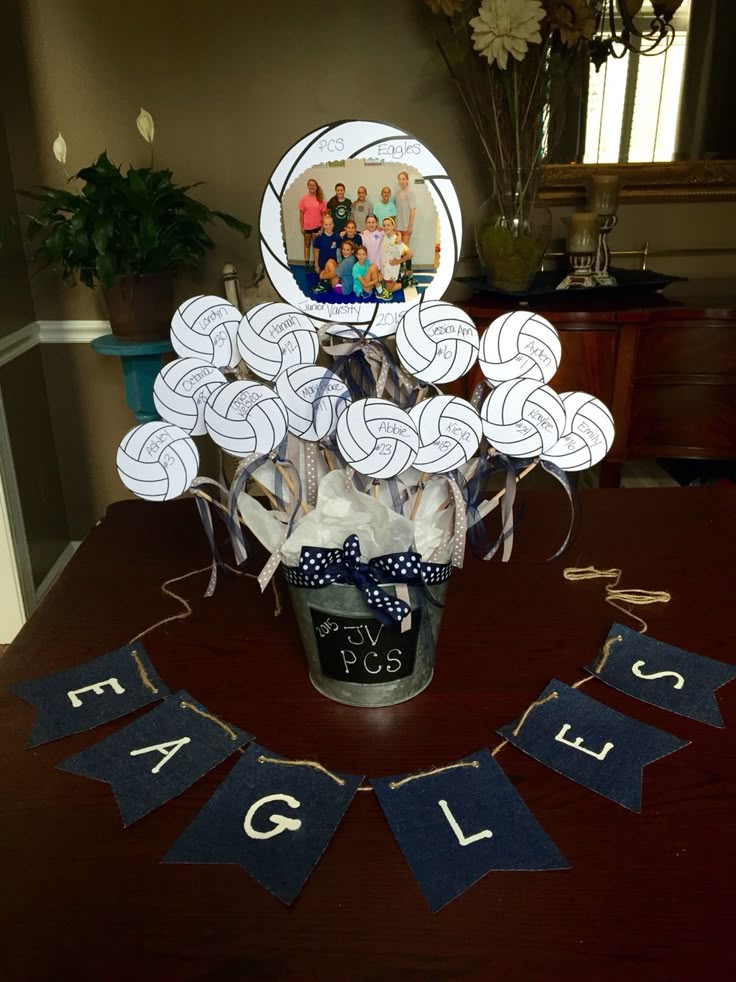 a vase filled with lots of white balls on top of a wooden table next to a banner