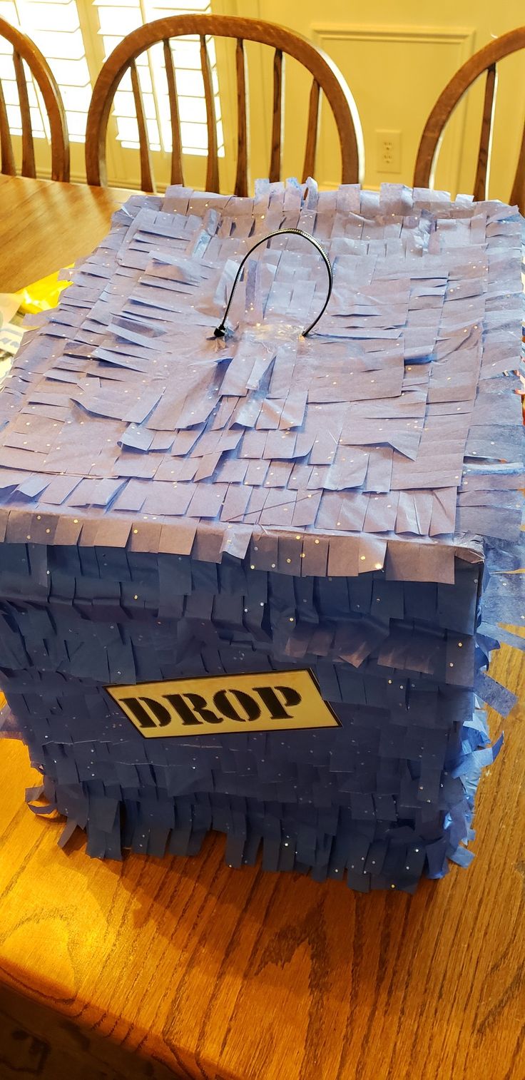 a blue box sitting on top of a wooden table covered in plastic wrap and adhesive tape