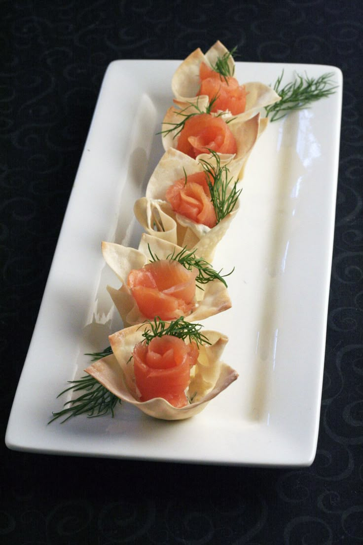 small appetizers with smoked salmon and dill garnish on a white plate