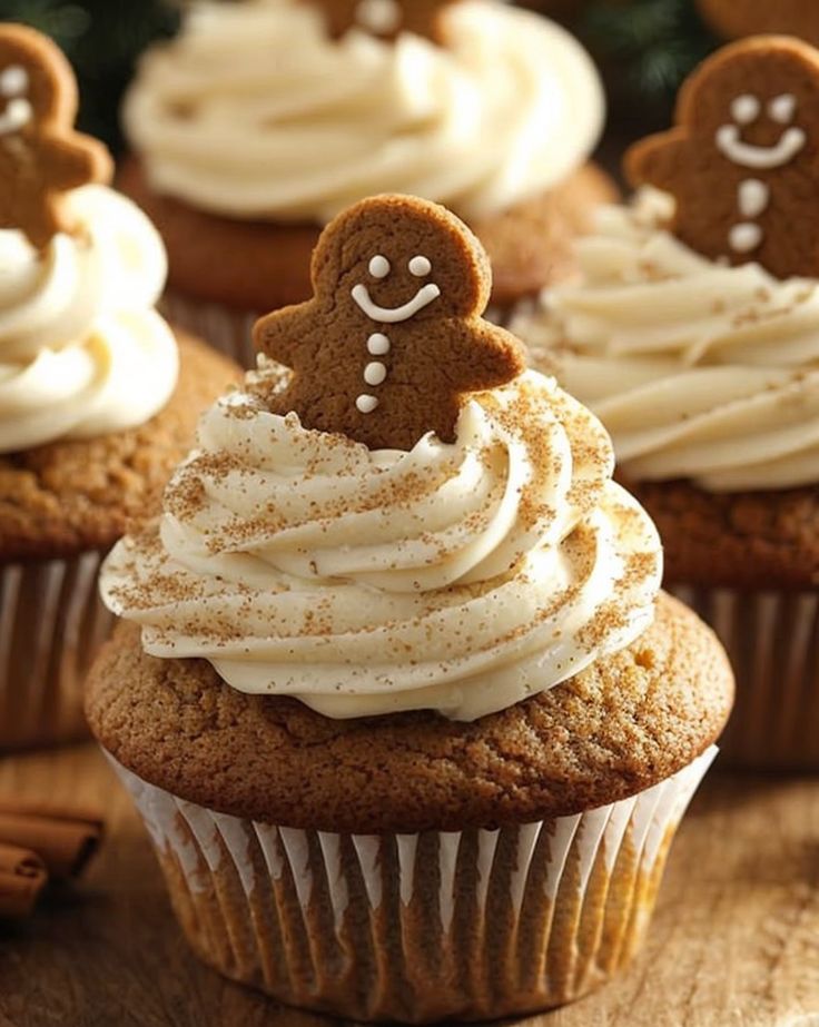 cupcakes with frosting and gingerbread decorations on top are sitting on a wooden table