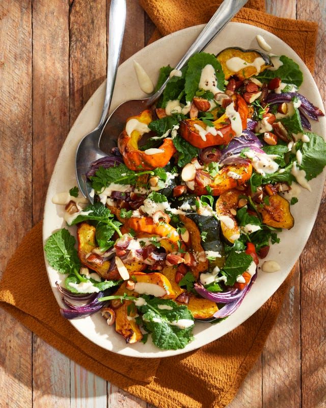 a white plate topped with salad on top of a wooden table next to silverware