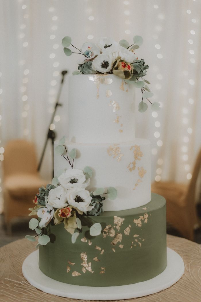 a white and green wedding cake with flowers on top