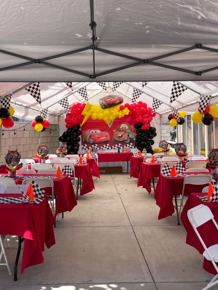 a red and black checkered table cloth covered area with white chairs, balloons and decorations