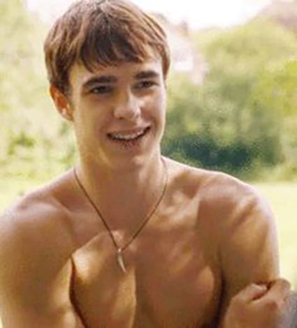 a shirtless young man sitting on a bench in the park with his hands clasped